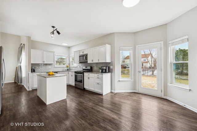 kitchen with appliances with stainless steel finishes, decorative backsplash, a kitchen island, and white cabinets