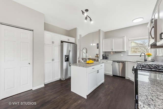 kitchen with a center island, white cabinets, appliances with stainless steel finishes, light stone countertops, and tasteful backsplash