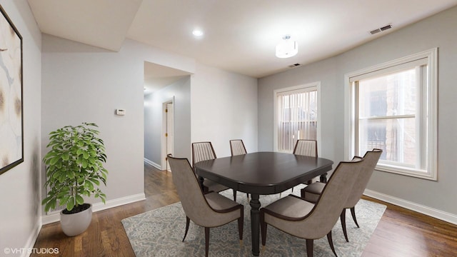 dining space with baseboards, visible vents, and dark wood-type flooring