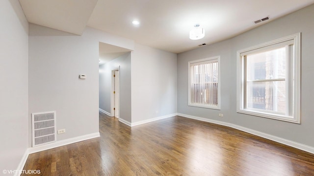 spare room with baseboards, visible vents, and dark wood-style flooring