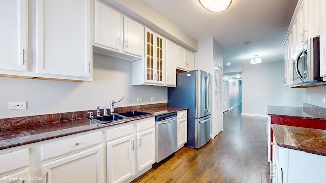 kitchen with glass insert cabinets, appliances with stainless steel finishes, white cabinets, and a sink