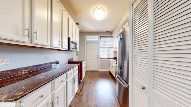 kitchen featuring white cabinets, dark stone counters, stainless steel appliances, and dark wood-style flooring