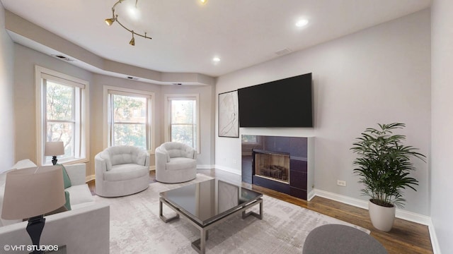 living room featuring baseboards, visible vents, a tiled fireplace, dark wood-type flooring, and recessed lighting