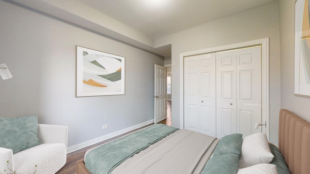 bedroom featuring a closet, baseboards, dark wood finished floors, and radiator heating unit