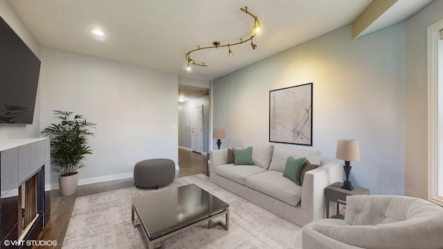 living room featuring baseboards, a fireplace, track lighting, and wood finished floors