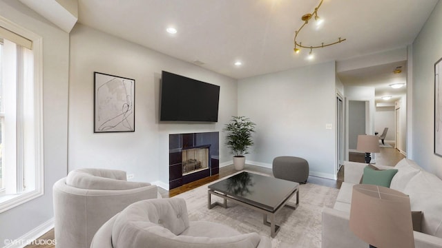 living room with light wood-type flooring, baseboards, a tiled fireplace, and recessed lighting