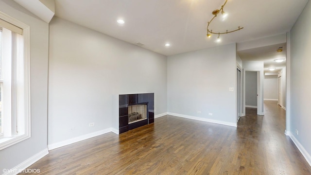 unfurnished living room with dark wood-style floors, a fireplace, baseboards, and recessed lighting