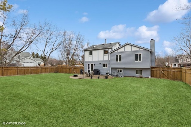 back of house featuring a fenced backyard, a yard, a chimney, and a patio