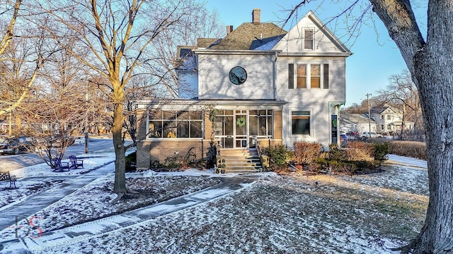 view of front facade with a chimney and a sunroom