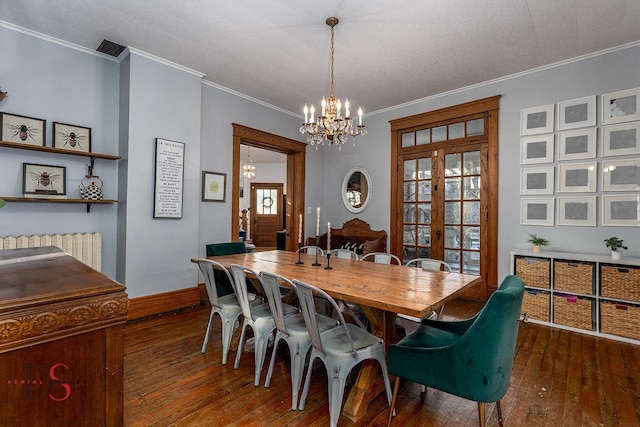 dining room with dark wood-type flooring, french doors, a chandelier, and ornamental molding