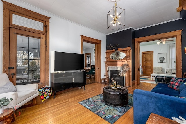 living room with ornamental molding, an inviting chandelier, a premium fireplace, and wood finished floors