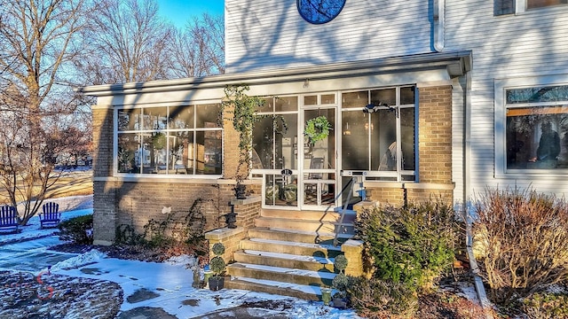 snow covered property entrance with brick siding