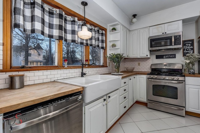 kitchen featuring open shelves, stainless steel appliances, butcher block counters, hanging light fixtures, and white cabinetry