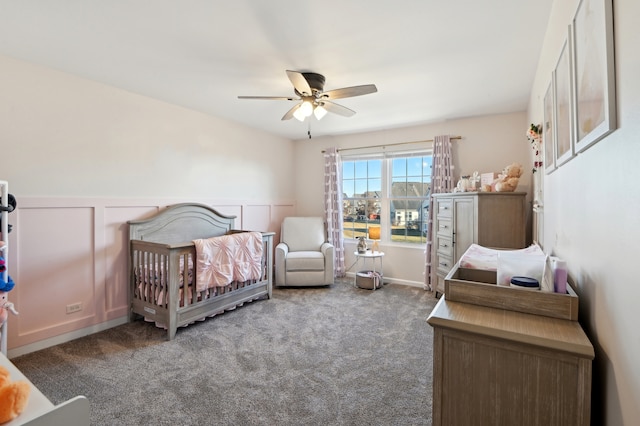 bedroom with a ceiling fan, wainscoting, and carpet flooring