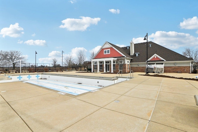 community pool featuring an outbuilding, a patio area, and fence