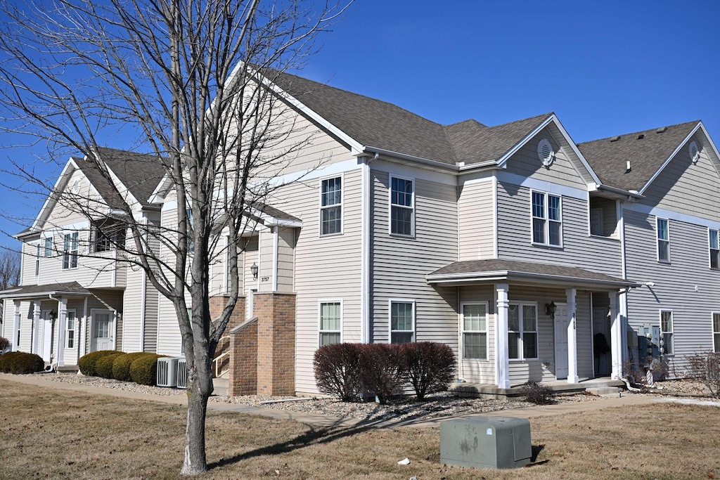 view of front of property with central air condition unit and roof with shingles