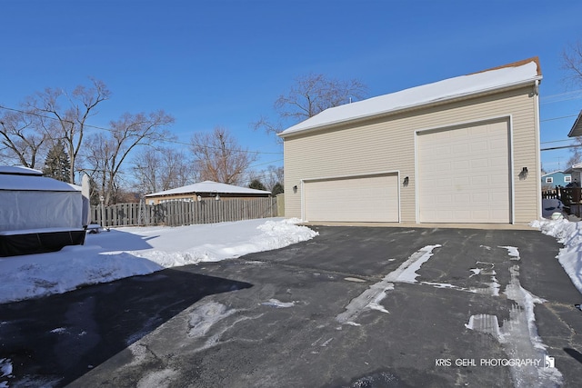 snow covered garage with a garage and fence