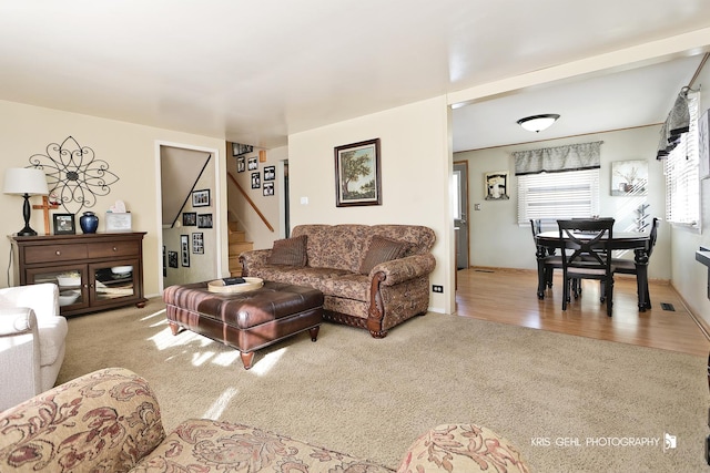 living room featuring carpet flooring, stairway, and visible vents