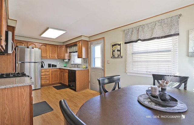 kitchen featuring brown cabinetry, stainless steel appliances, decorative backsplash, light countertops, and light wood-type flooring