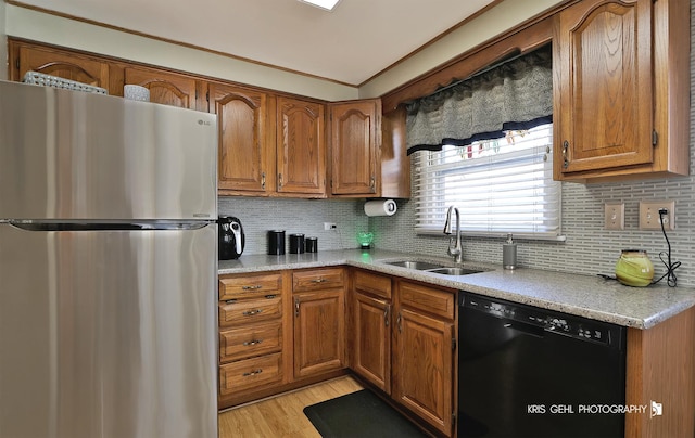 kitchen featuring brown cabinets, a sink, backsplash, freestanding refrigerator, and dishwasher