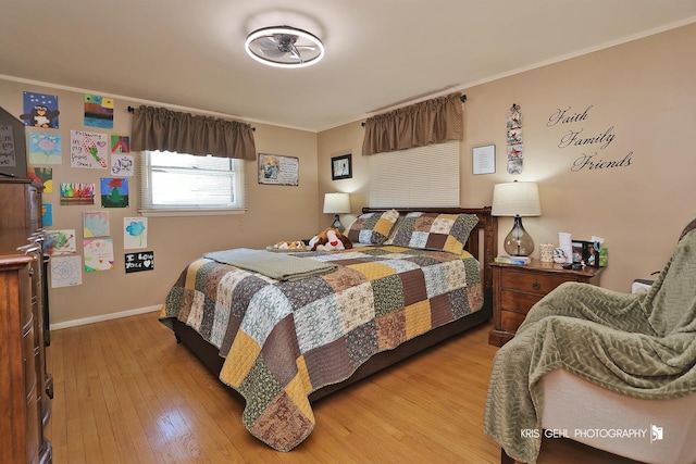 bedroom featuring baseboards, crown molding, and light wood-style floors