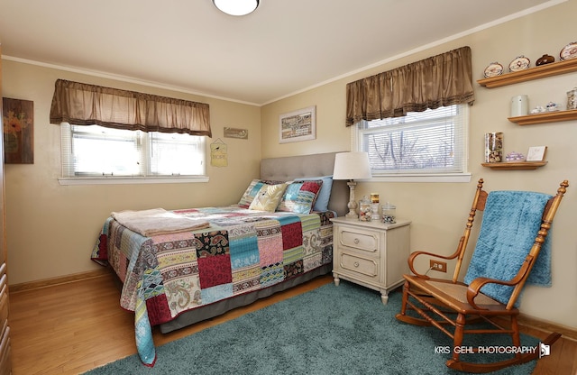 bedroom featuring multiple windows, wood finished floors, baseboards, and ornamental molding