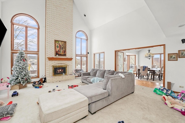 living room featuring carpet floors, a fireplace, high vaulted ceiling, and a notable chandelier