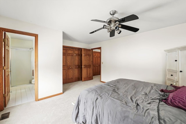 bedroom featuring a closet, visible vents, light carpet, ceiling fan, and ensuite bath