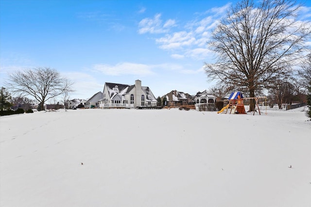 yard covered in snow with a playground and a residential view