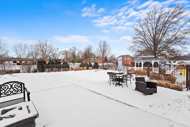 snow covered patio with a residential view, fence, and a gazebo