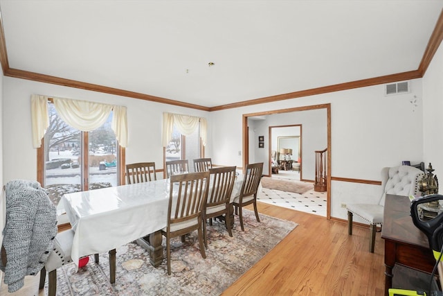 dining space featuring crown molding, baseboards, visible vents, and light wood-style floors