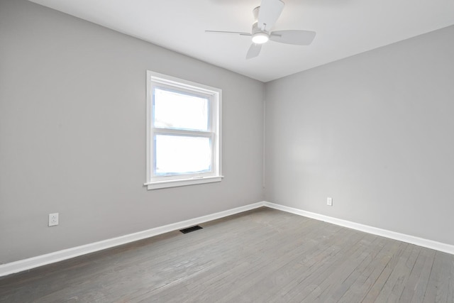 spare room featuring visible vents, ceiling fan, baseboards, and wood finished floors