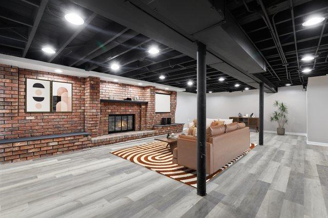 living room featuring baseboards, a fireplace, brick wall, and wood finished floors