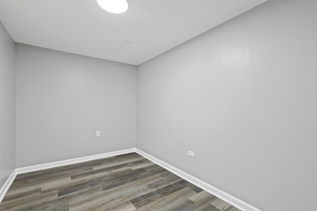 empty room with dark wood-style flooring and baseboards