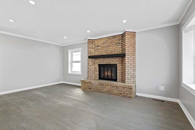 unfurnished living room featuring crown molding, a brick fireplace, wood finished floors, and baseboards