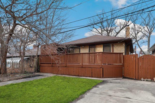 exterior space featuring brick siding, a chimney, a gate, a wooden deck, and a front yard