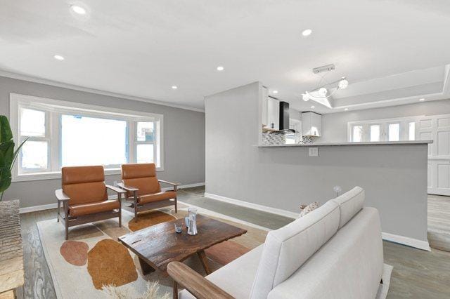 living room featuring ornamental molding, light wood-style floors, recessed lighting, and baseboards