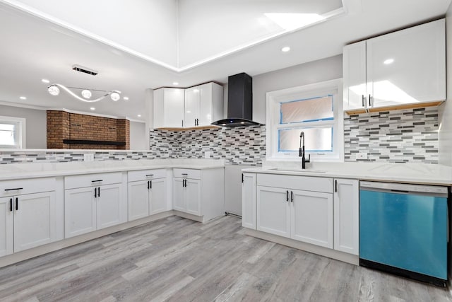 kitchen featuring dishwashing machine, wall chimney exhaust hood, light wood-style flooring, white cabinetry, and a sink