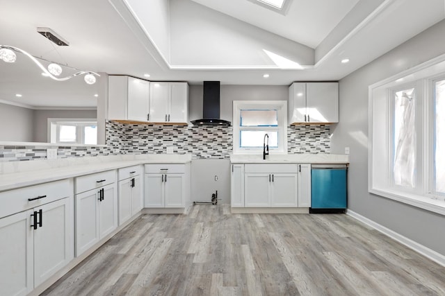 kitchen featuring dishwashing machine, plenty of natural light, a sink, and wall chimney exhaust hood