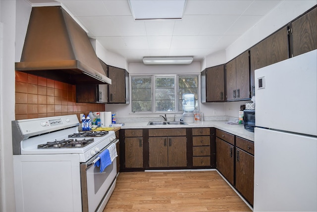 kitchen with white appliances, a sink, exhaust hood, light wood-style floors, and light countertops