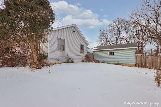 snow covered rear of property featuring fence