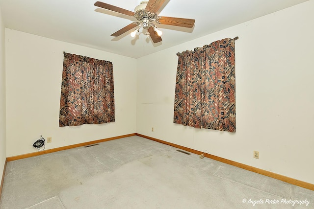 empty room featuring ceiling fan, carpet floors, visible vents, and baseboards