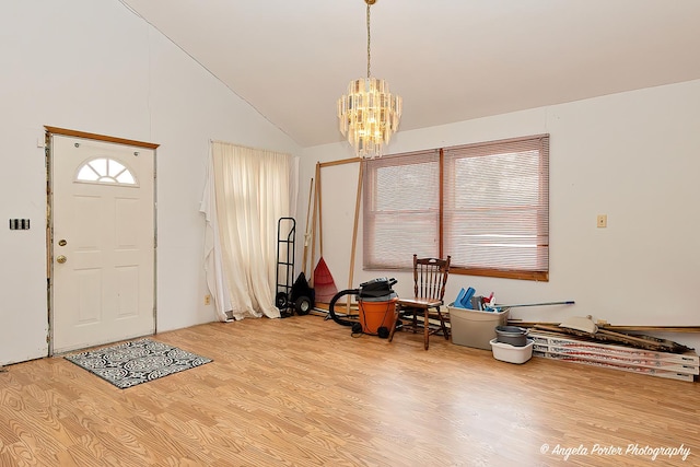 foyer featuring vaulted ceiling, light wood finished floors, and a notable chandelier