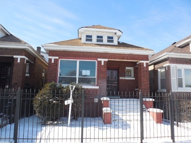 bungalow-style house featuring brick siding, a fenced front yard, and a gate