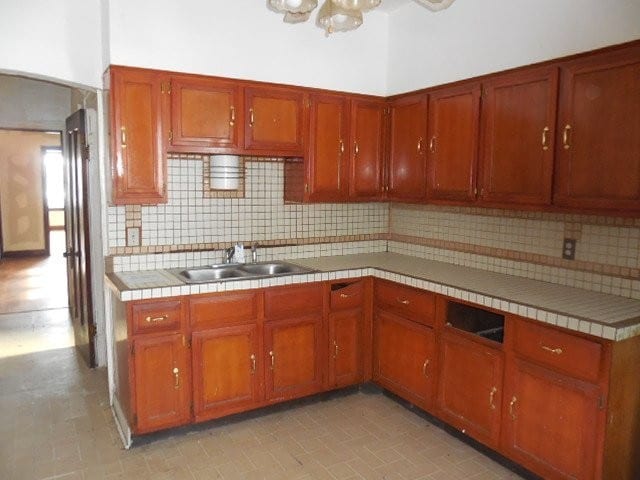 kitchen featuring tasteful backsplash, tile counters, brown cabinets, and a sink