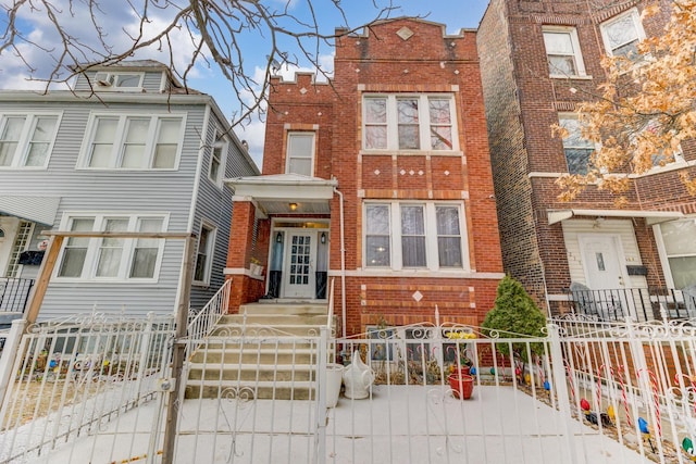 townhome / multi-family property with a fenced front yard, a gate, and brick siding