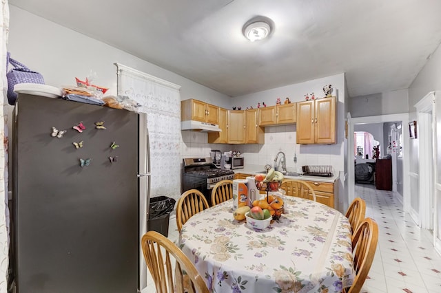 kitchen with tasteful backsplash, light countertops, appliances with stainless steel finishes, light brown cabinets, and under cabinet range hood