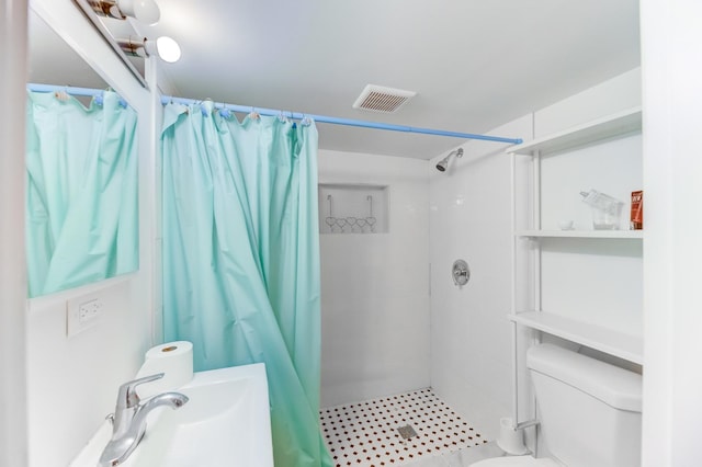 bathroom featuring toilet, a sink, a tile shower, and visible vents