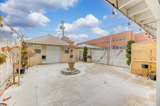 view of patio / terrace with a garage, driveway, an outdoor structure, and fence