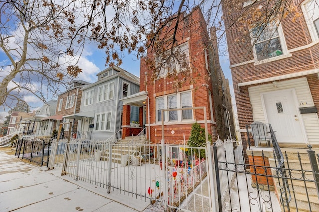 view of front of property featuring a fenced front yard, a residential view, a gate, and brick siding